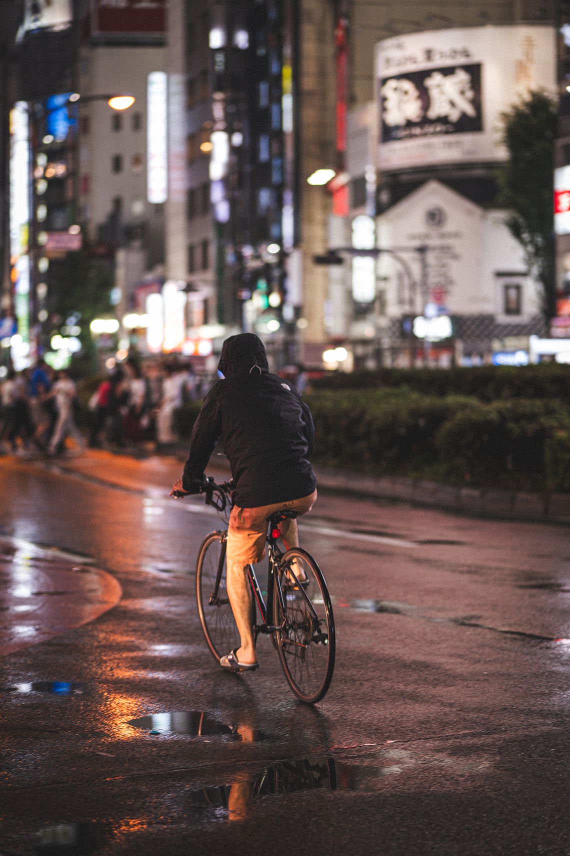 Cyclist riding through wet city streets at night