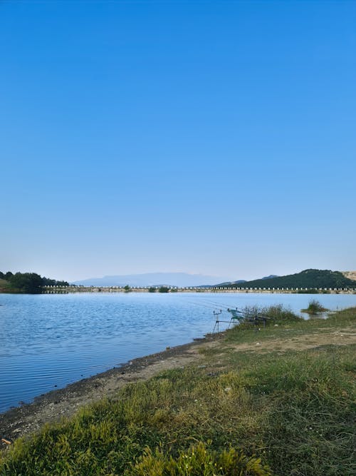 View of a Body of Water and Hills in the Horizon under Clear Blue Sky 