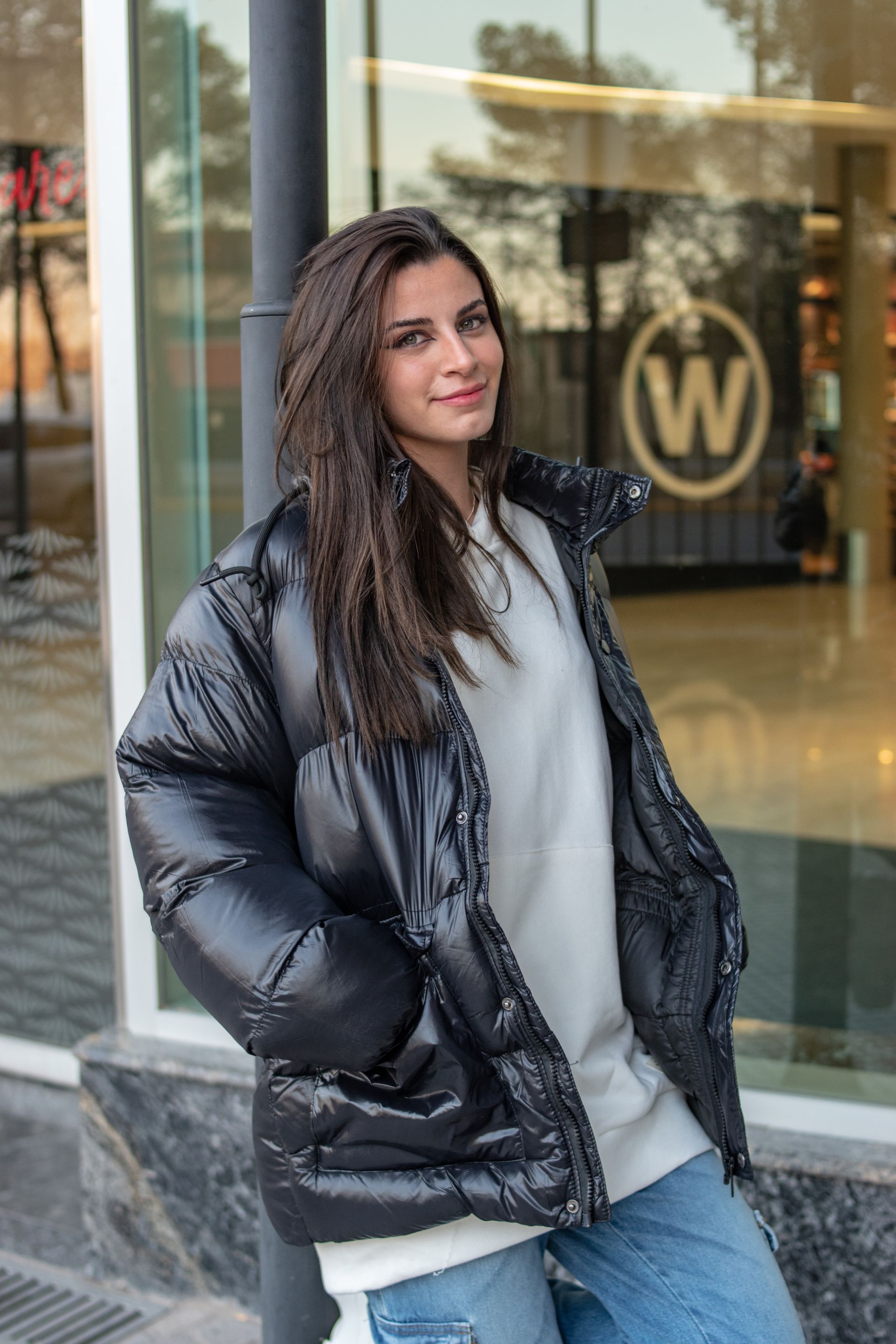 Mulher sorrindo de jaqueta puffer preta na rua