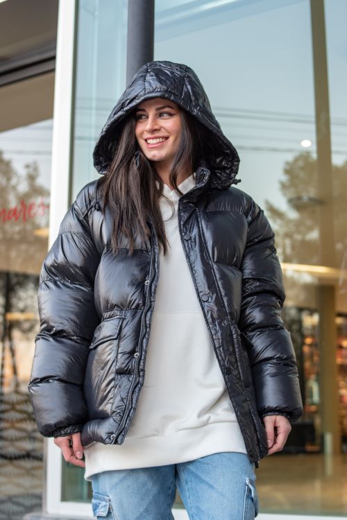 Free A cheerful woman in a stylish black puffer jacket smiling in a city environment. Stock Photo