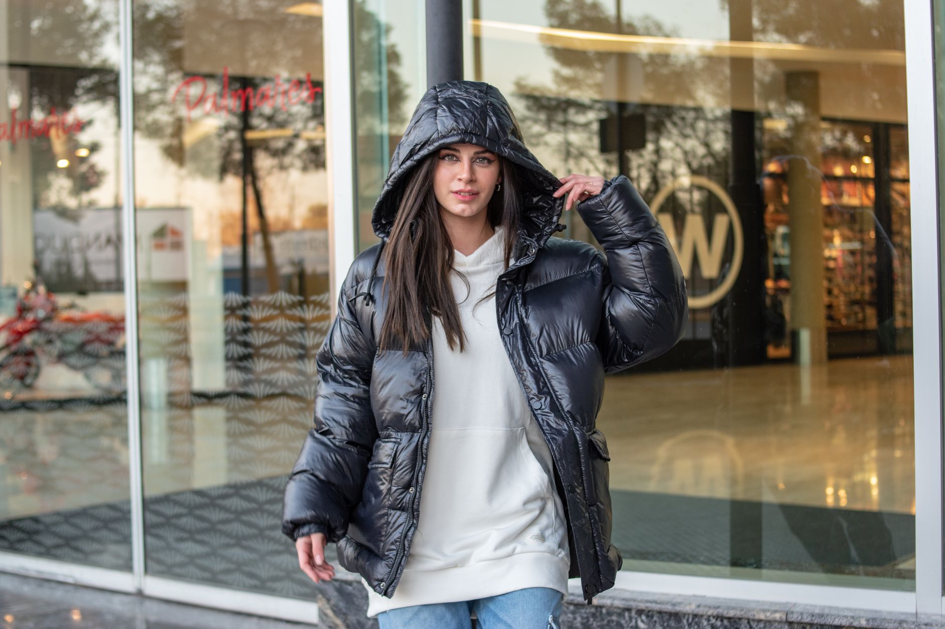 Femme en doudoune noire oversize portée avec un sweat blanc en ville