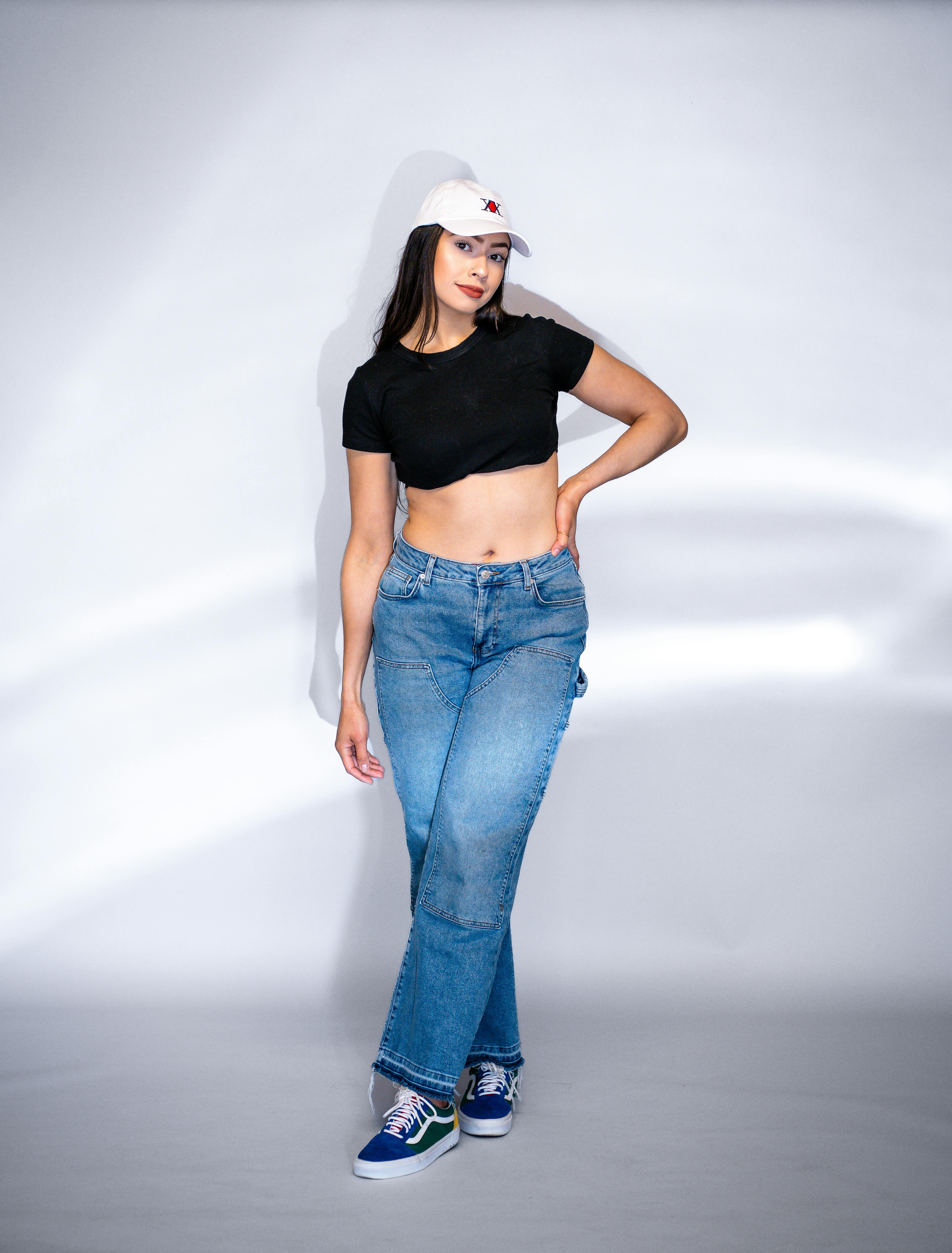 Young Woman Posing in Black Crop Top, Blue Jeans and White Baseball Cap