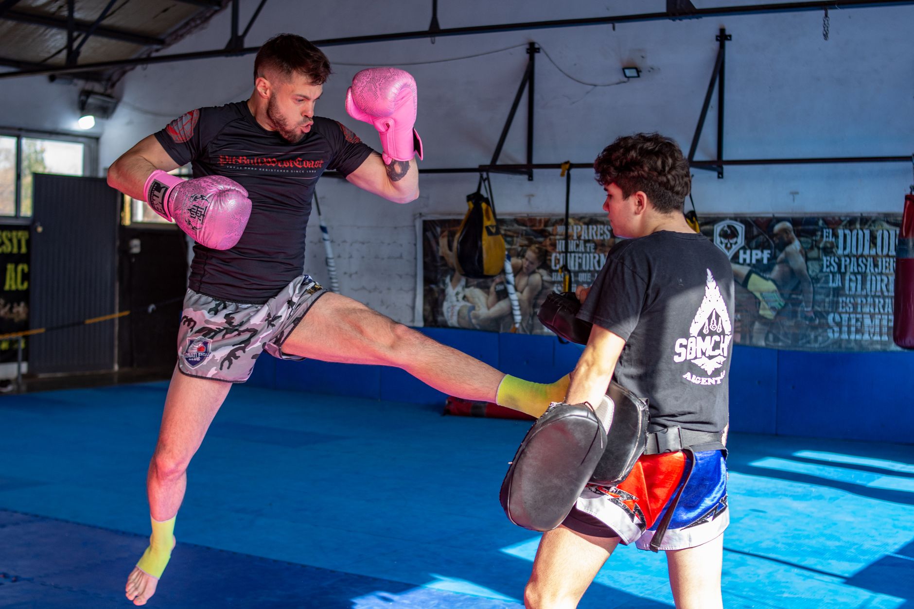 Dynamic kickboxing training featuring two men sparring in a gym setting.