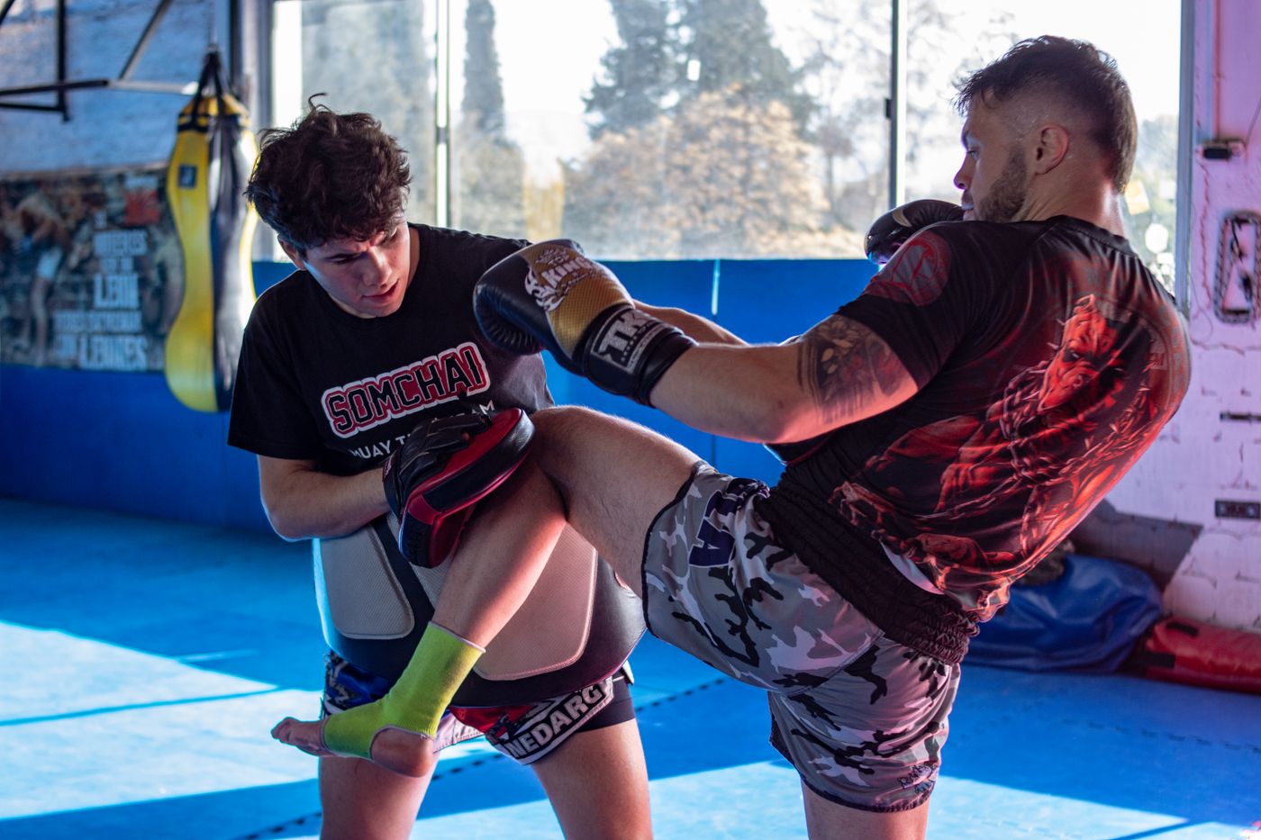 Adult kickboxers practising controlled sparring in a martial arts gym.