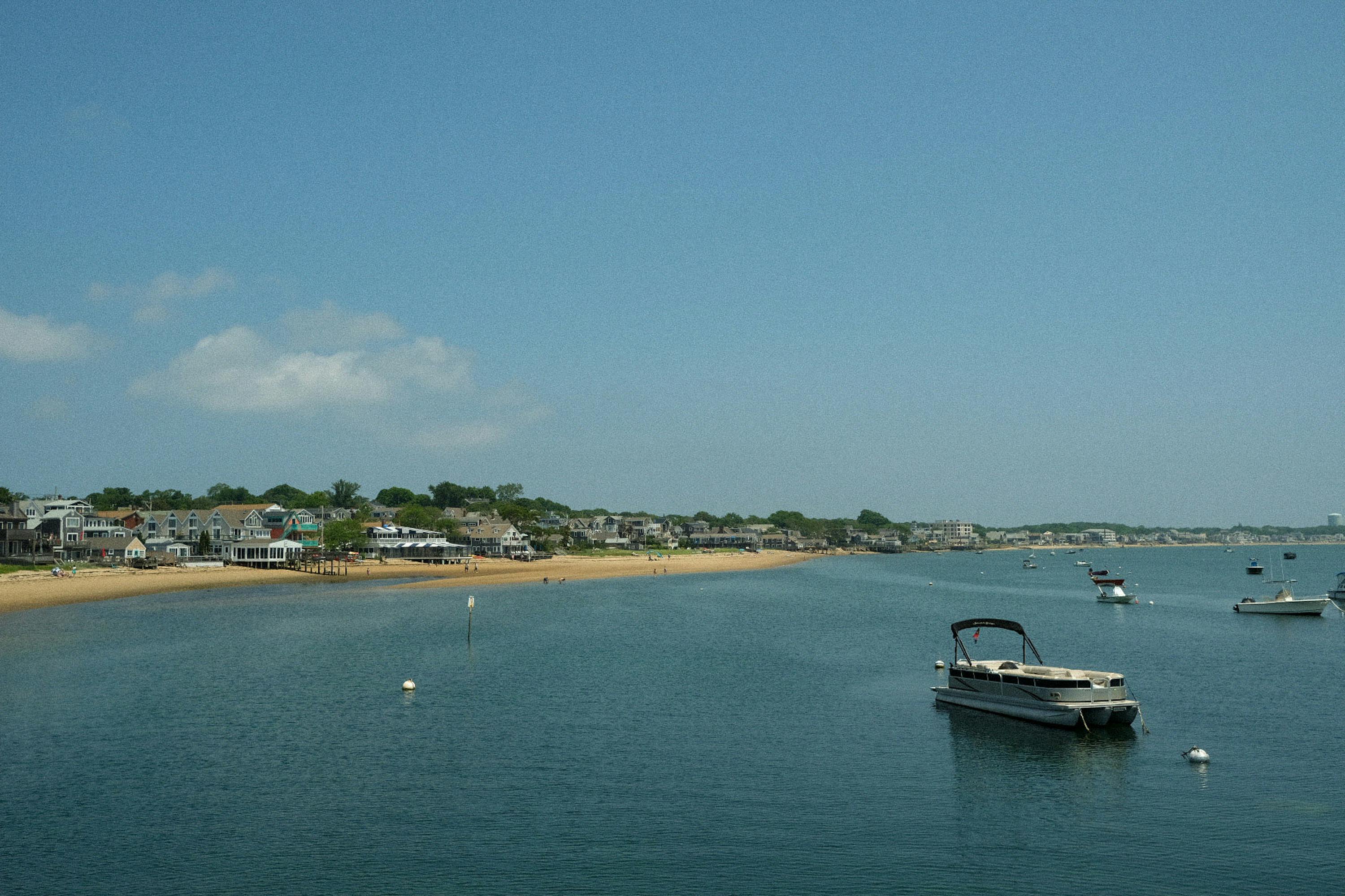 Scenic view of Nantucket coast with moored boats under a clear summer sky.