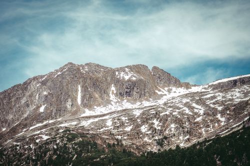 Free Rugged mountain landscape with snow patches under a vibrant blue sky. Stock Photo