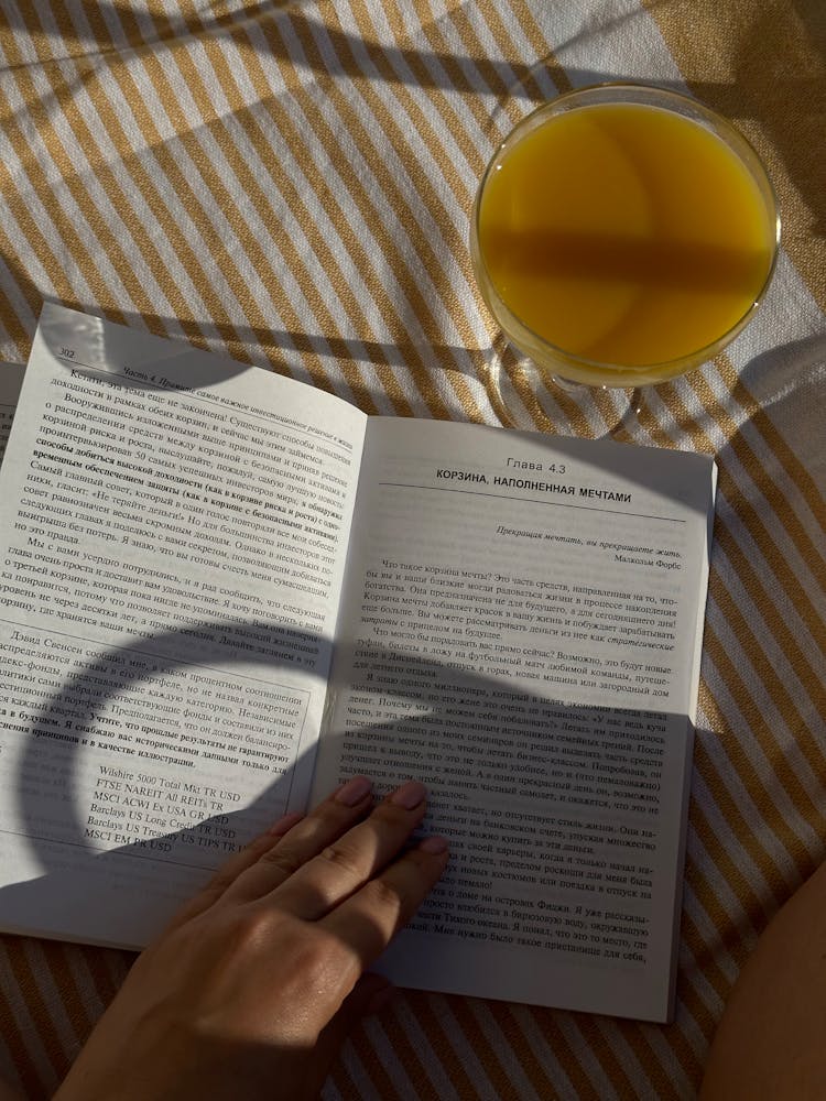 Woman Hand On Open Book With Glass Near