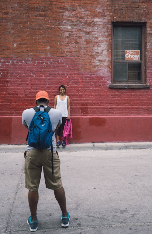 бесплатная Мужчина смотрит на женщину, опираясь на кирпичную стену здания Стоковое фото