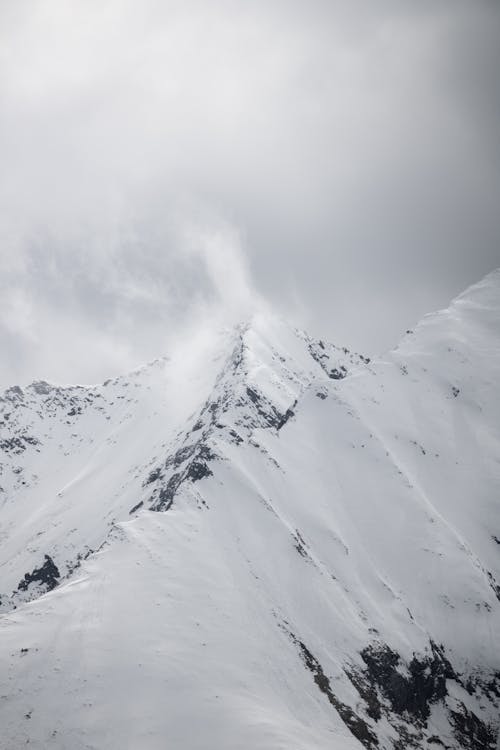 A snowy mountain with a large snow covered peak