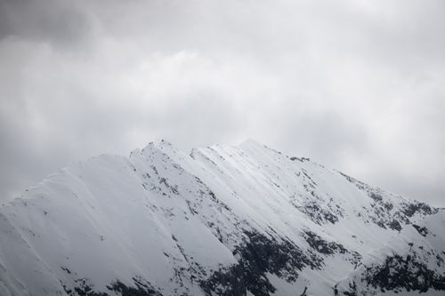 Free Dramatic snow-covered mountain peaks in Tirol, Austria, under a cloudy winter sky. Stock Photo
