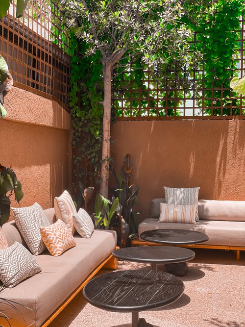 Free Stylish outdoor patio featuring sofas, coffee tables, and lush greenery. Stock Photo