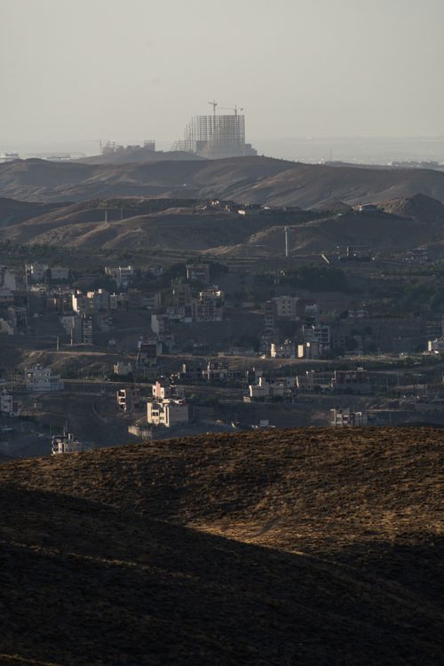 Free Distant view of Mashhad city with rolling hills under a warm sunset glow. Stock Photo