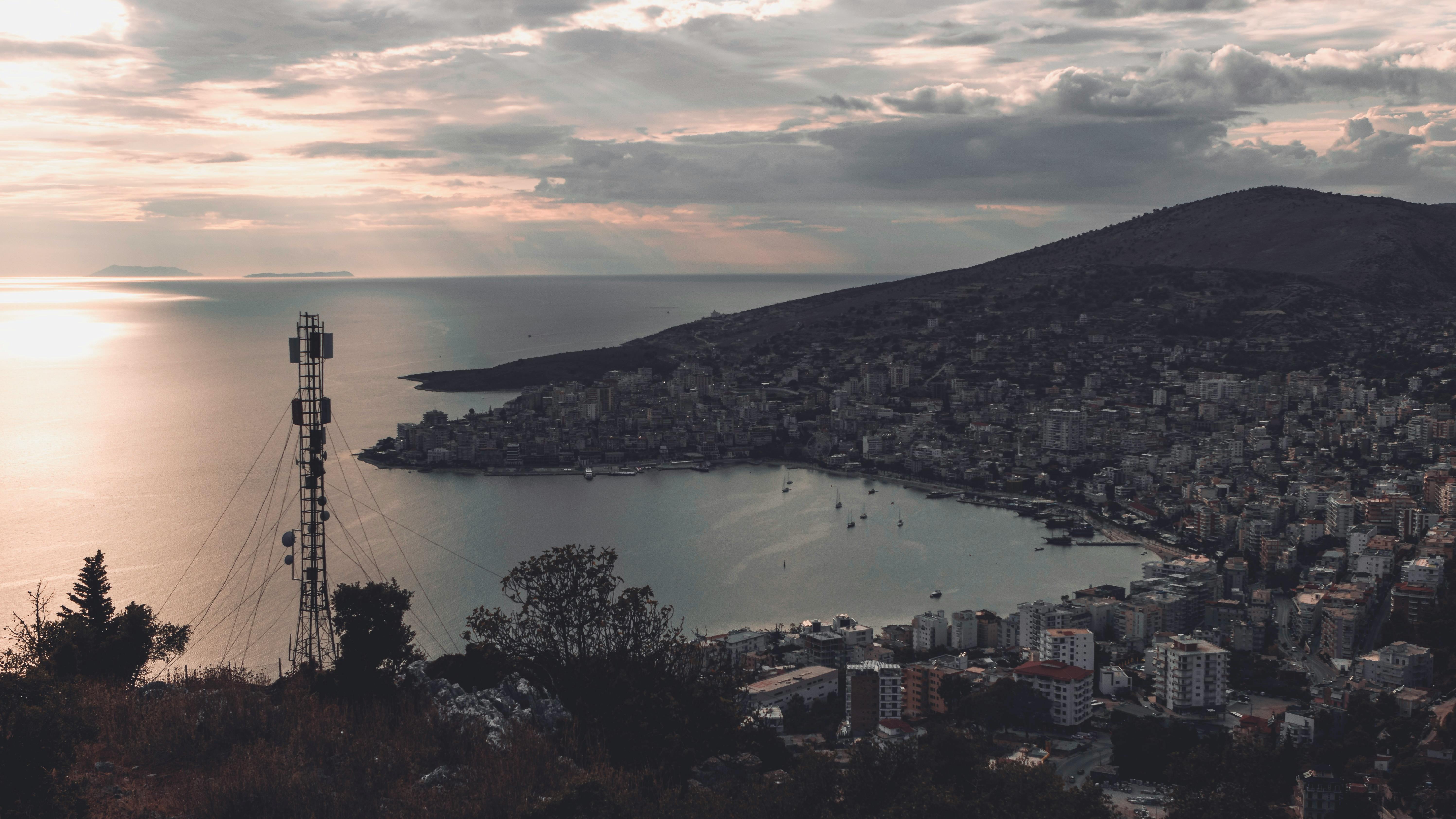 A serene view of Saranda, Albania cityscape and coastline at dusk with a distant television tower.