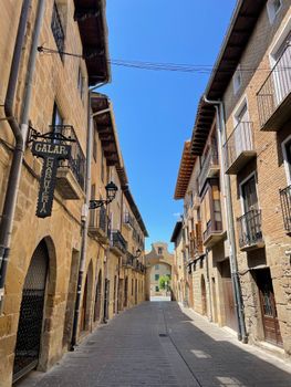 Explore a picturesque historic street lined with rustic architecture under a clear blue sky.