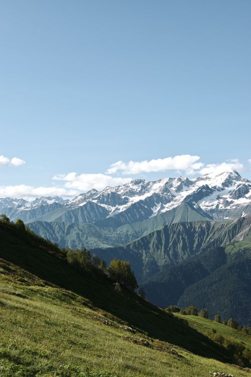 Free Breathtaking view of a snowcapped mountain range in summer with a clear blue sky. Stock Photo
