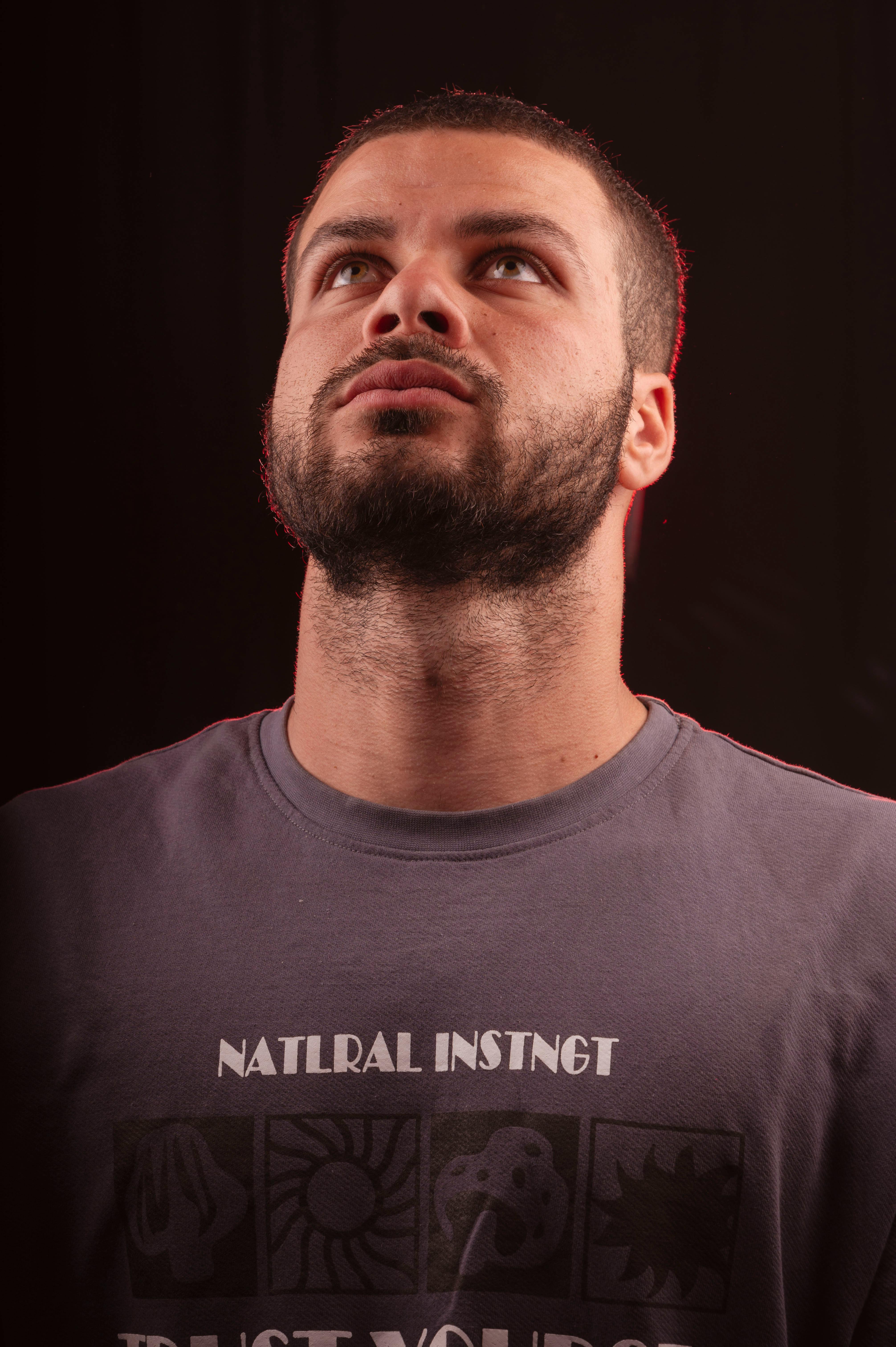 Bearded man in casual t-shirt gazing upwards, captured in a studio setting.