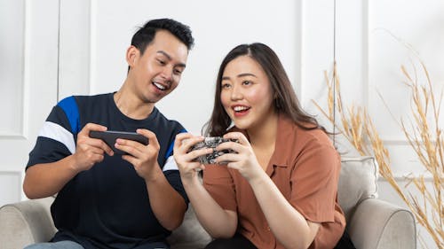 Beautiful young couple in love playing game at home, sitting at the living room