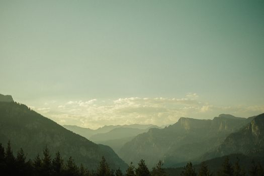 Serene mountain landscape with mist and soft morning light over the valleys.
