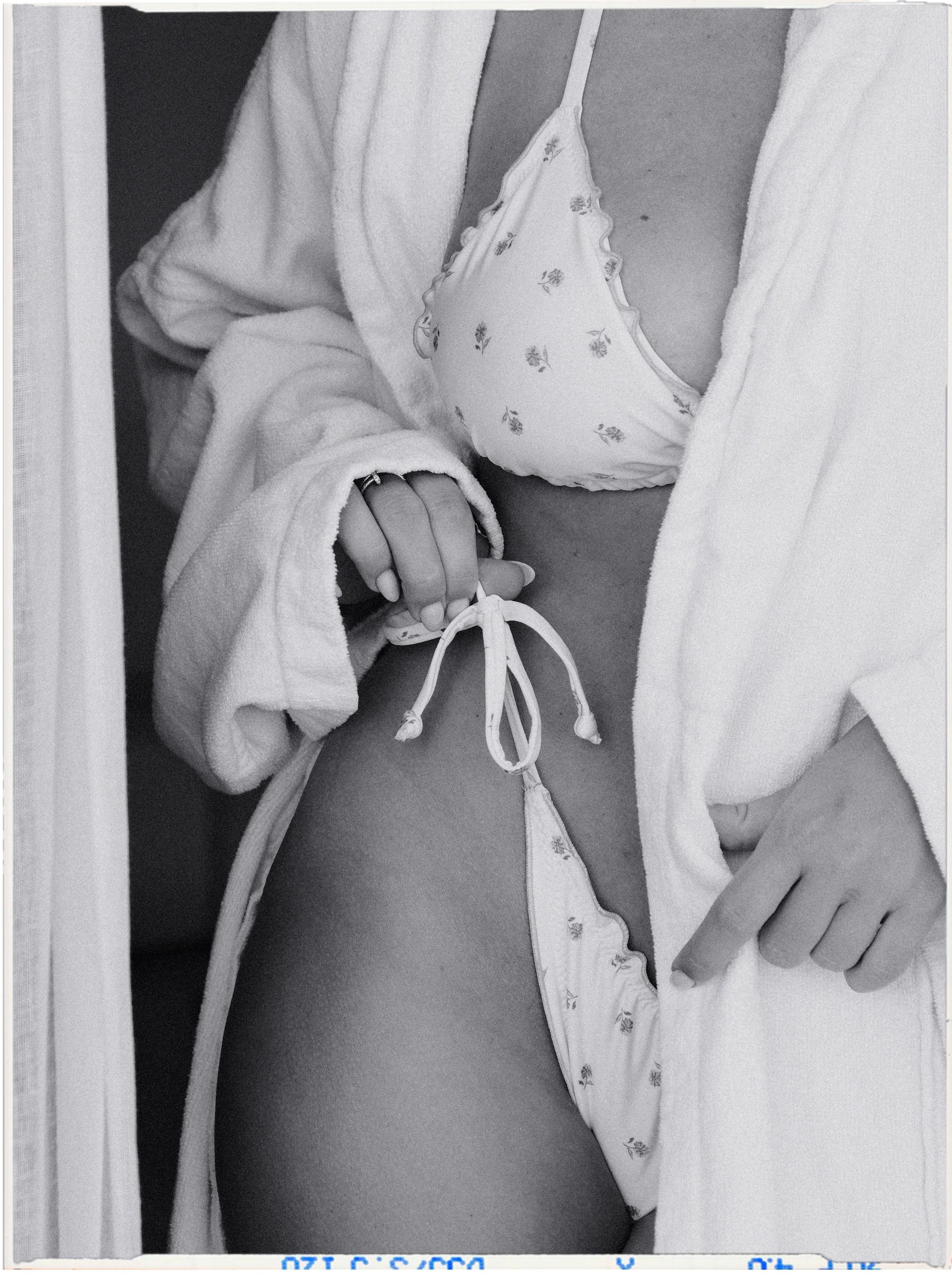 Artistic black and white photo featuring a woman in swimwear and robe, emphasizing patterns.