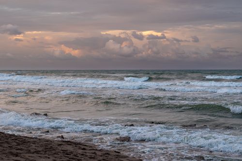 Free Waves crash on the Las Palmeras shore under a dramatic sunset sky, capturing nature's raw power. Stock Photo