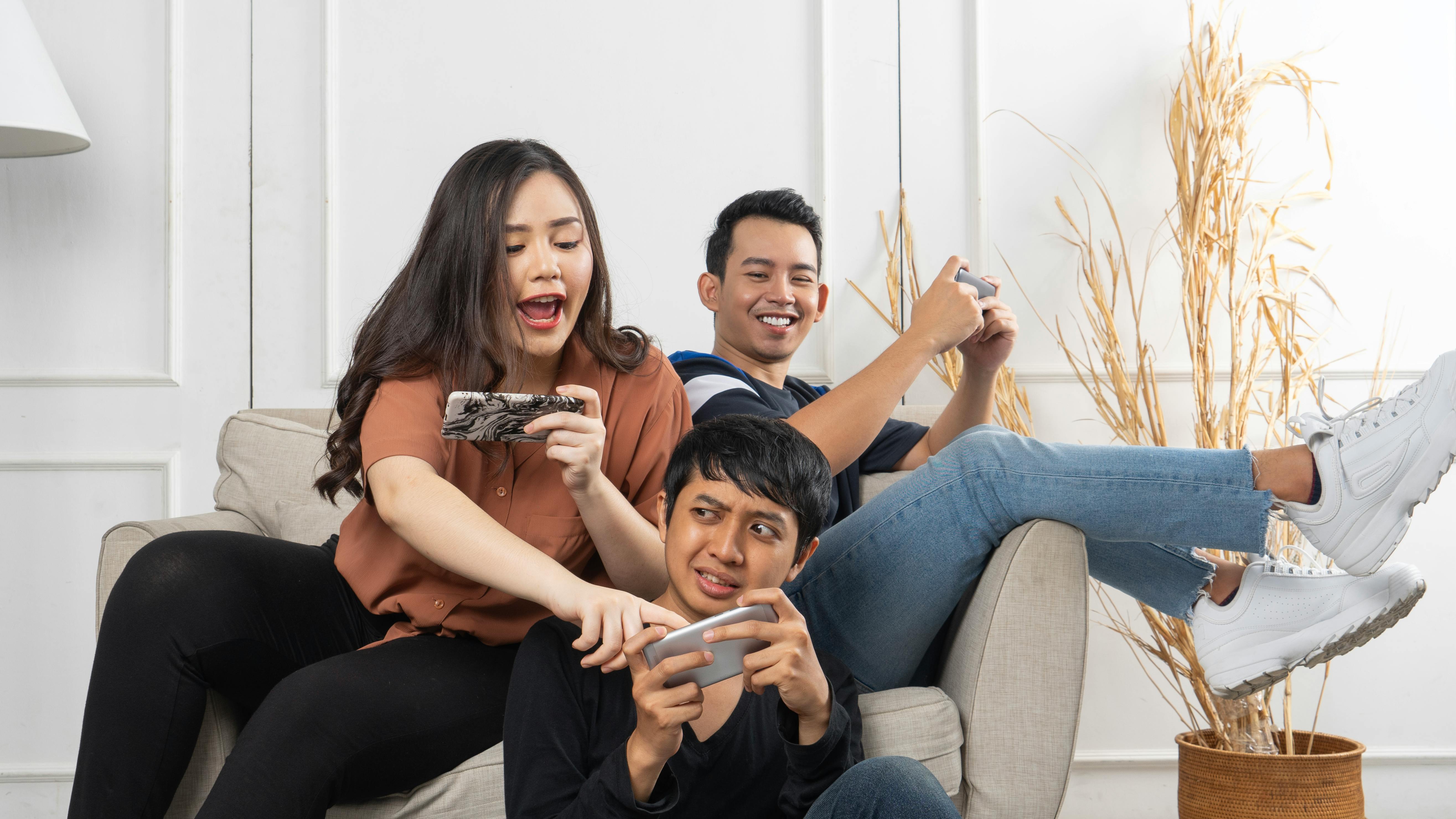 group of young asian people sitting and addicted to playing mobile online games together