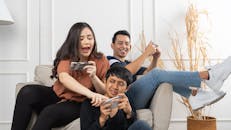 Group of young Asian people sitting and addicted to playing mobile online games together