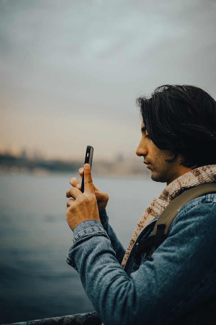 Man With Smartphone Taking Pictures On Sea Shore