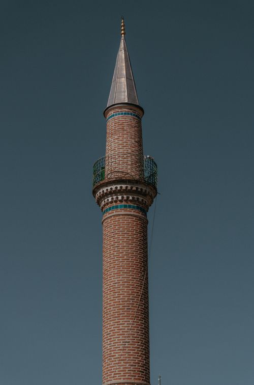 Free Vertical shot of a traditional brick minaret standing tall against a clear blue sky. Stock Photo