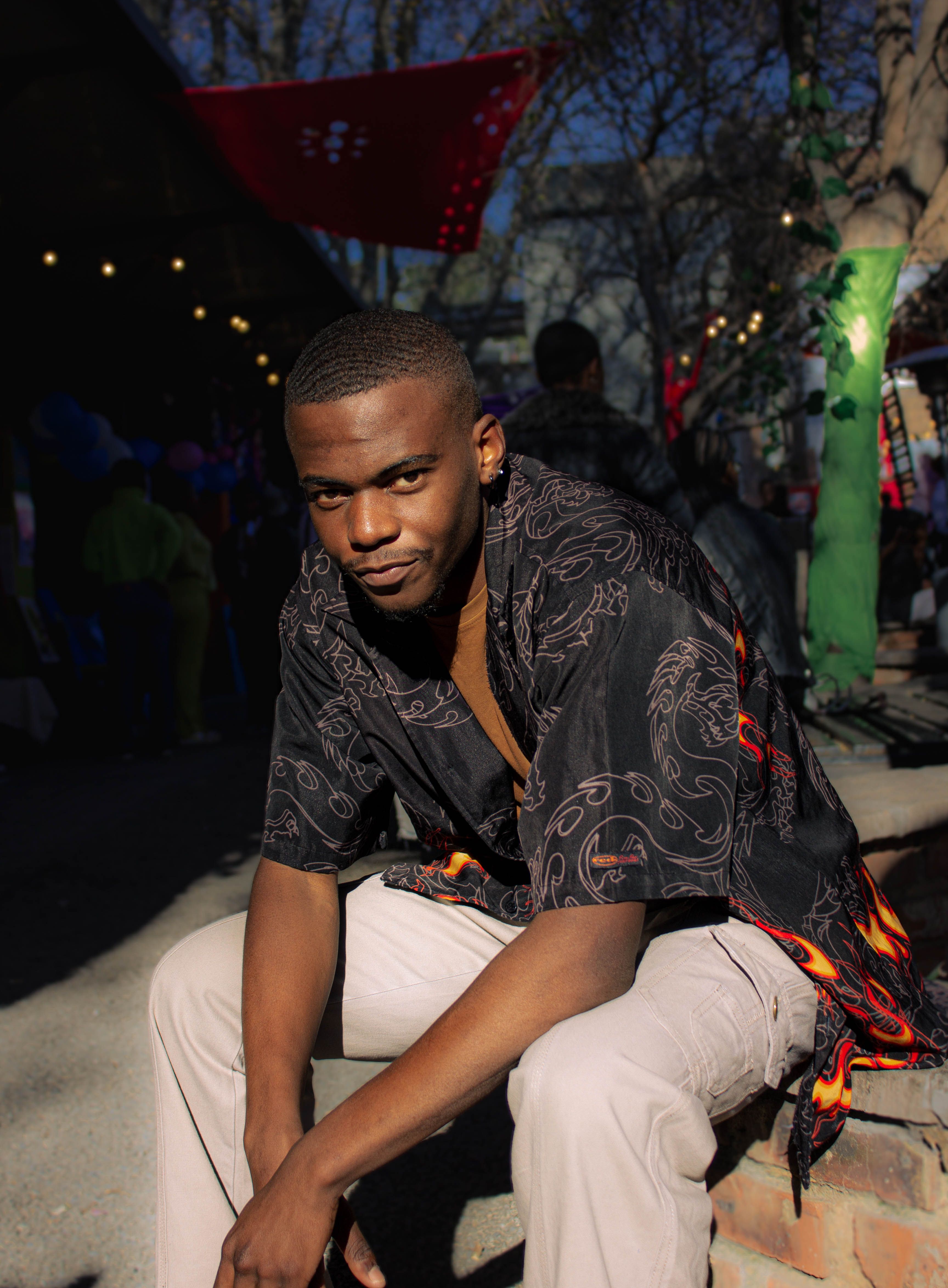 Young man posing confidently in a stylish black shirt outdoors, showcasing fashion and charisma.
