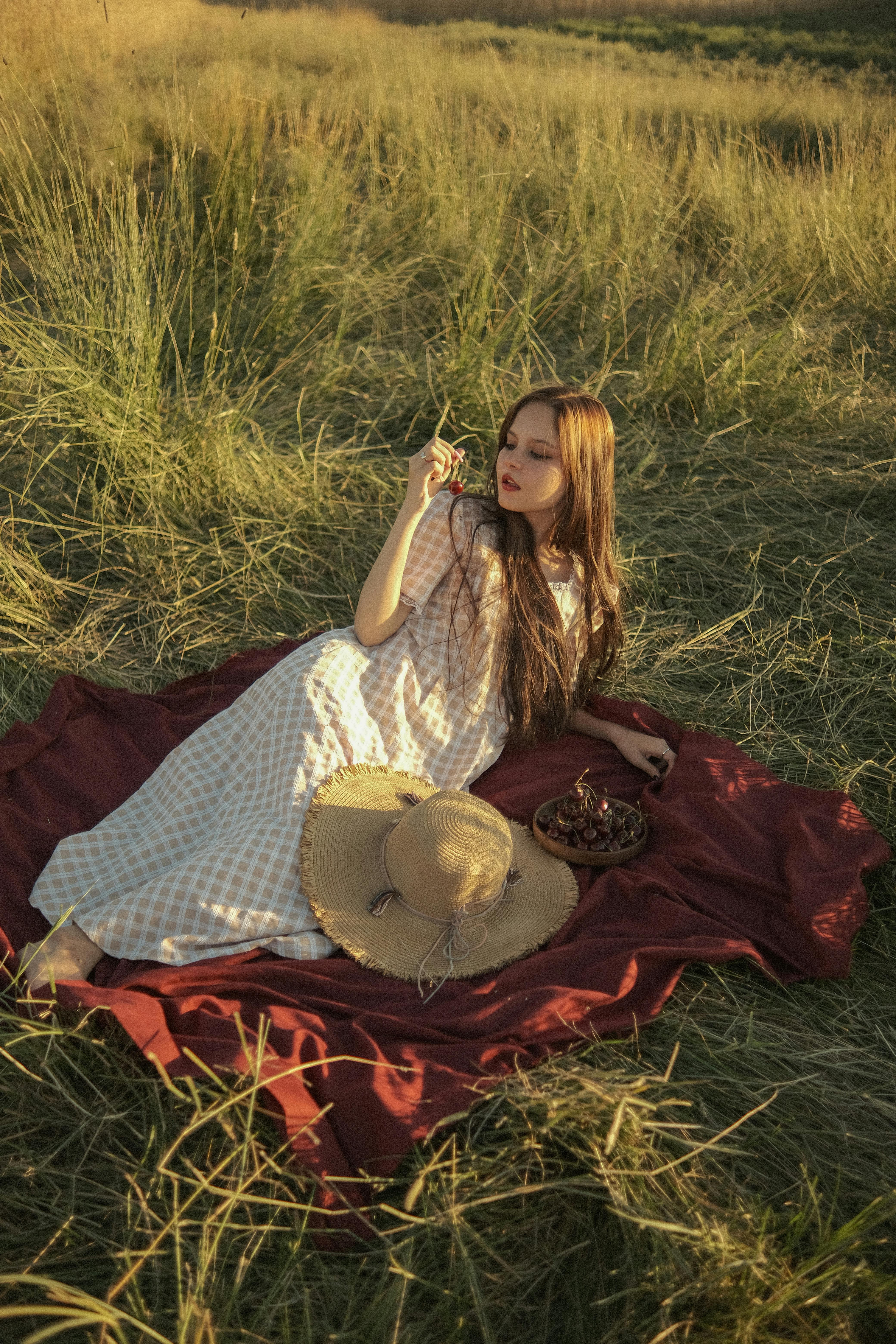 Young woman enjoying a serene summer picnic in a sunlit meadow.