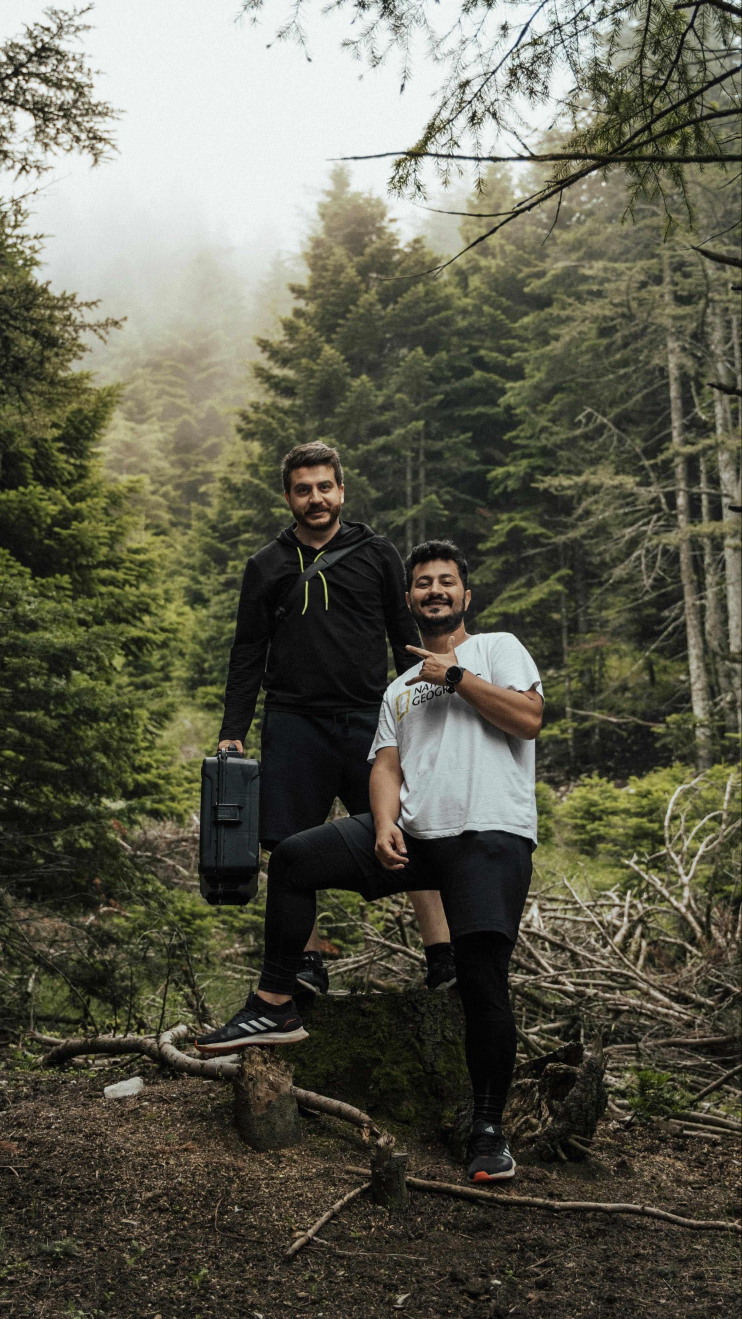 Two men posing in a foggy forest setting, ideal for themes of adventure and nature exploration.
