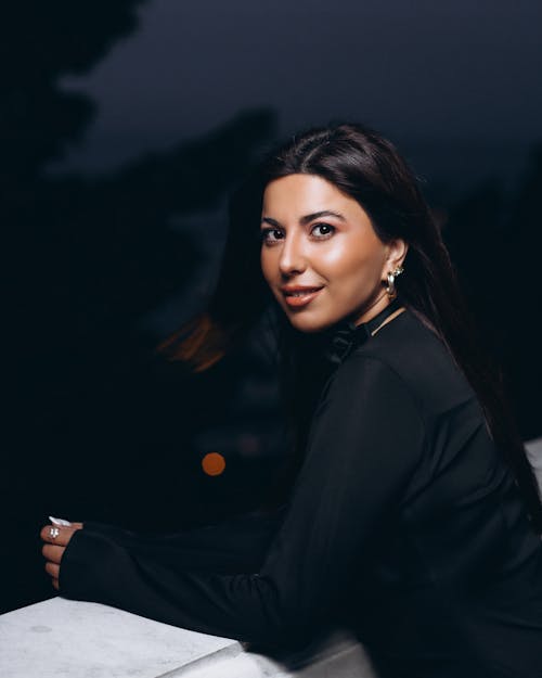 Free Portrait of a Pretty Brunette Standing on a Balcony at Night Stock Photo