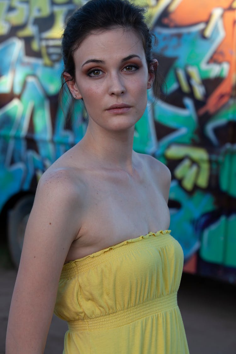 Young Woman In A Dress Standing Outside On The Background Of A Truck Covered In Graffiti 