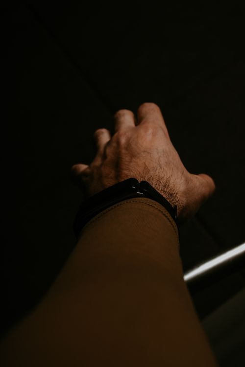Free A man's hand in a dramatic gesture reaches into a dark space, illuminated softly. Stock Photo