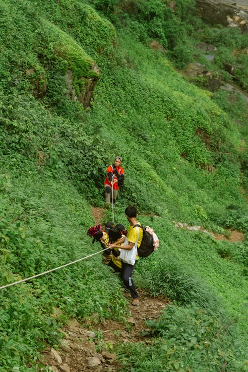 Hikers Walk Uphill and Hold Rope