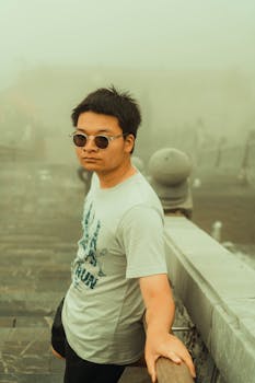 Portrait of a man wearing sunglasses in an urban mist, standing on a foggy day.