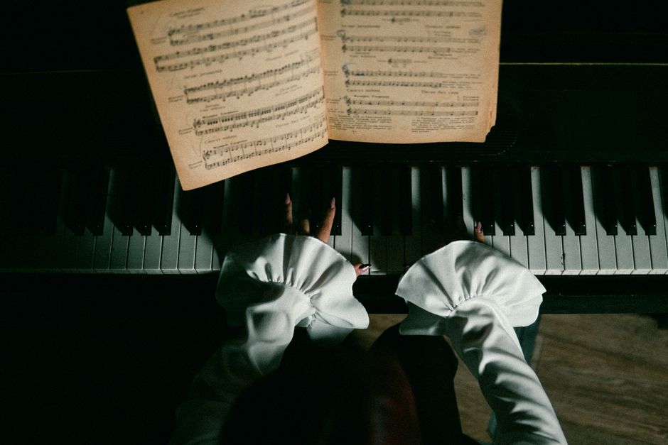 Overhead view of a woman playing piano with sheet music, showcasing the elegance of music.