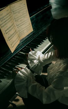 A woman plays the piano in a dimly lit room, creating a moody musical ambiance.