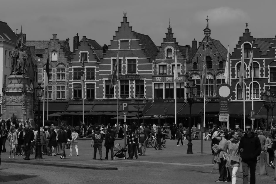 Black and white photo of Bruges Market Square with medieval buildings and a bustling crowd.