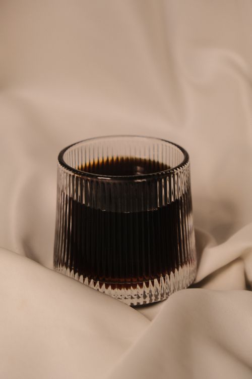 Free A stylish glass of rich coffee on a draped fabric background, emphasizing its texture and warmth. Stock Photo