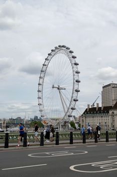 A vibrant scene capturing people walking along Westminster Bridge with the London Eye in the background.