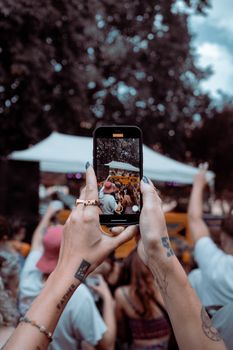 Hands holding a smartphone capturing a vibrant outdoor concert in Bristol, UK.