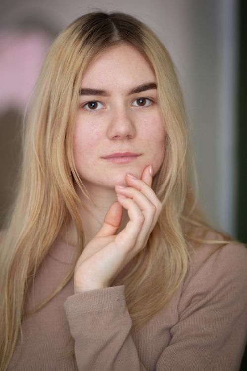 Free Close-up portrait of a young blonde woman indoors, capturing a natural and elegant look. Stock Photo