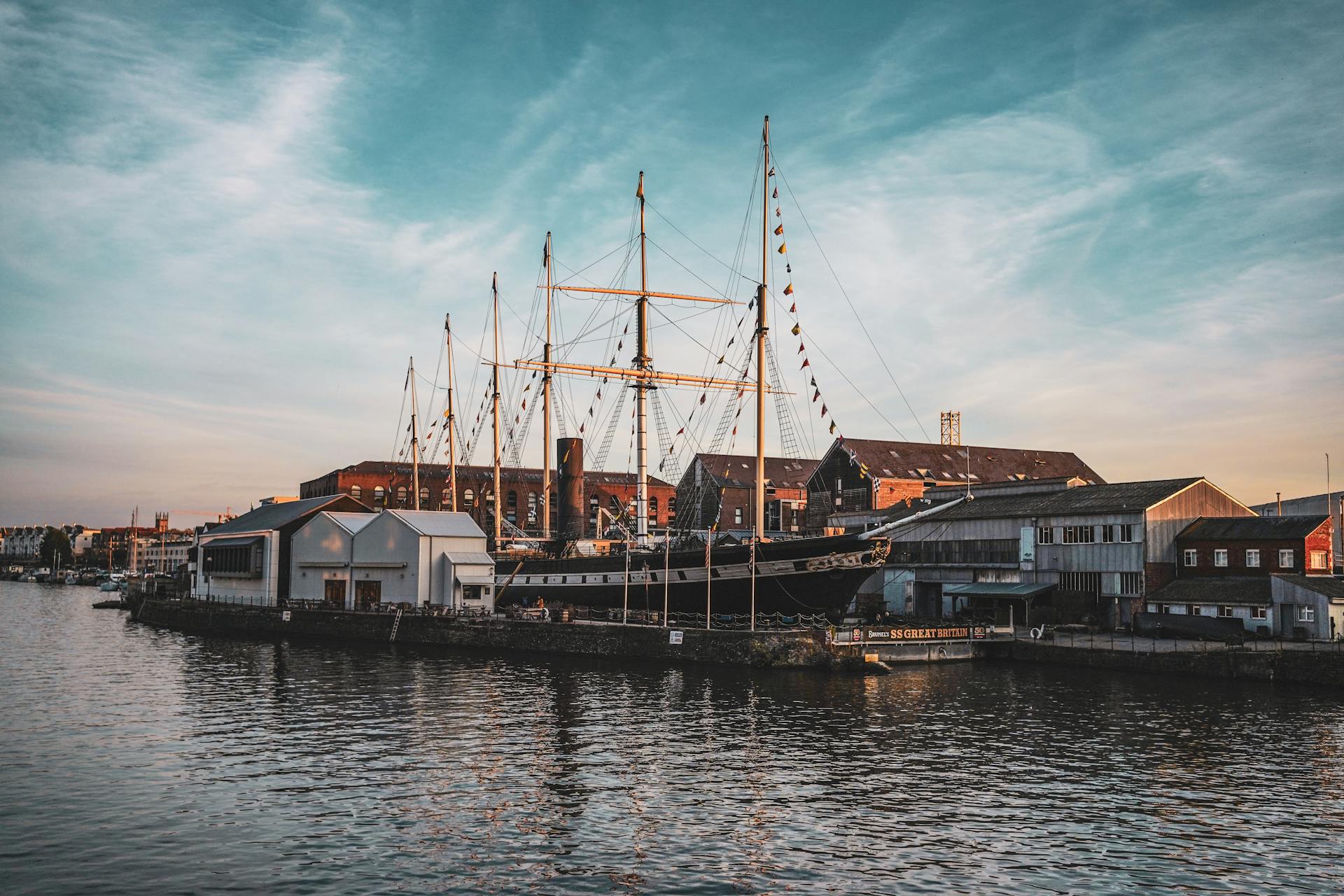 A majestic ship in a bustling urban harbor at sunset, reflecting the beauty and history of maritime heritage.