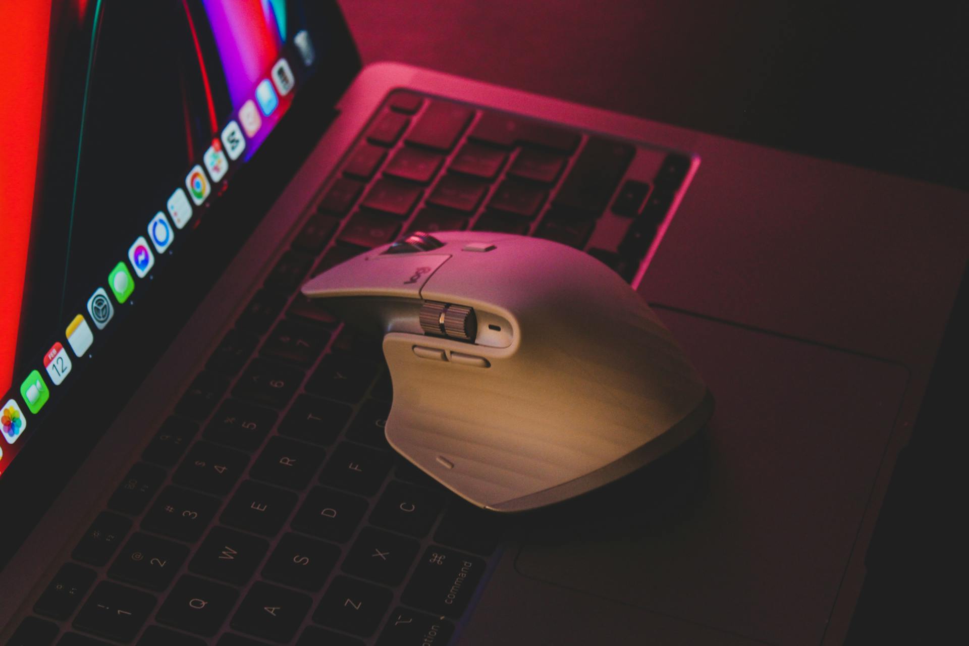 Close-up of a wireless mouse on a laptop keyboard in low light, highlighting modern technology.