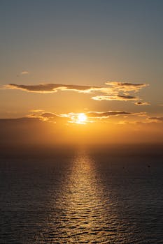 Stunning sunset over the Atlantic Ocean at Los Gigantes, Tenerife, with vibrant sky and golden reflections.