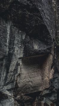 A detailed close-up shot highlighting the rough texture and erosion marks on a moody rock surface.