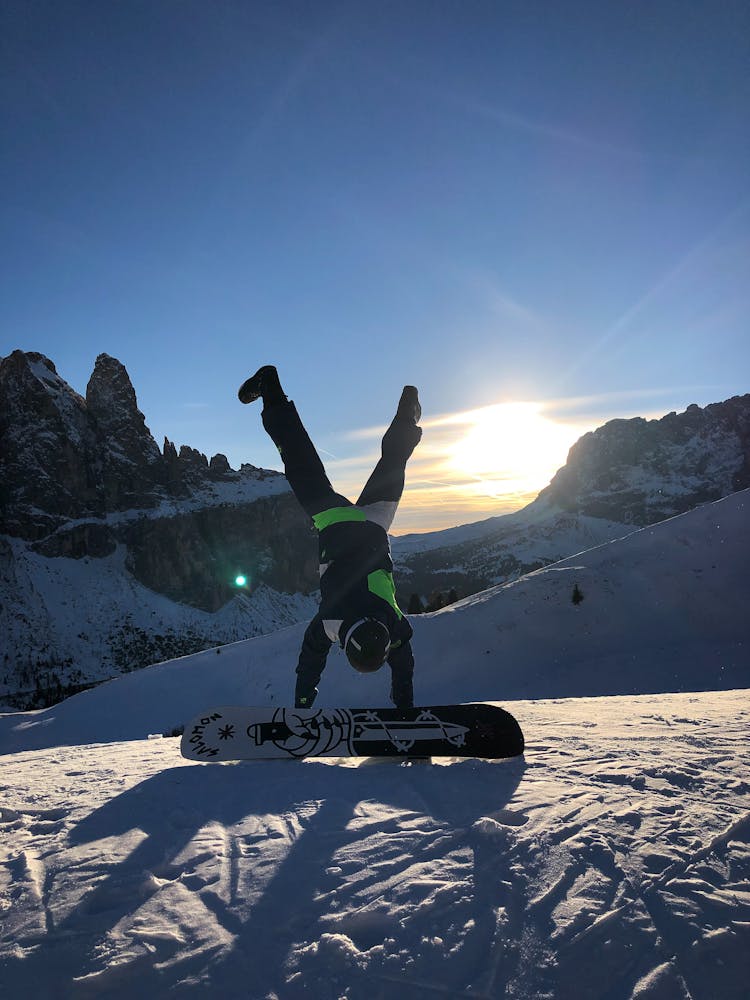 Photo Of Person Doing Handstand Near Snowboard