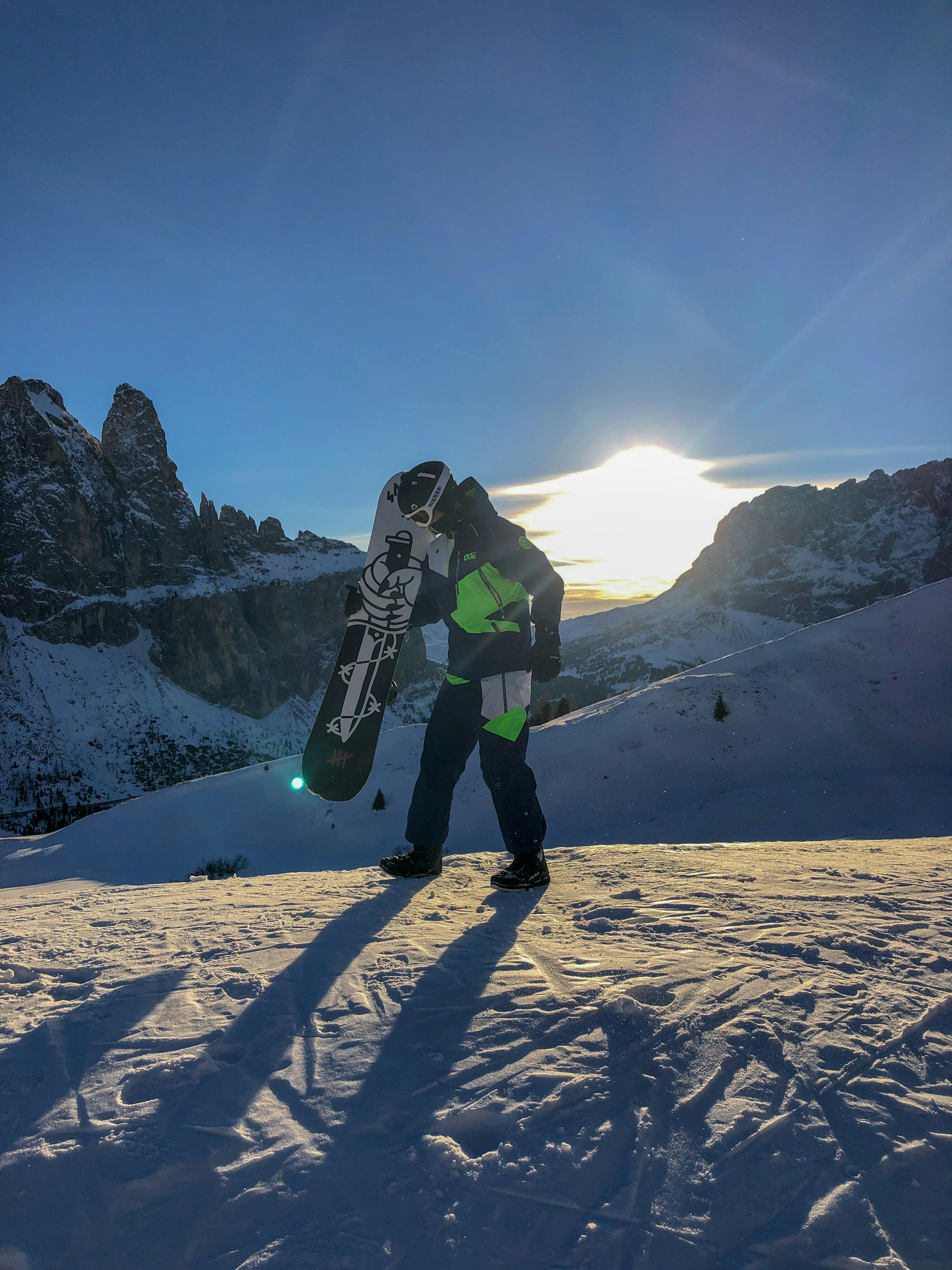 雪山でスノーボードを持っている男 無料の写真素材