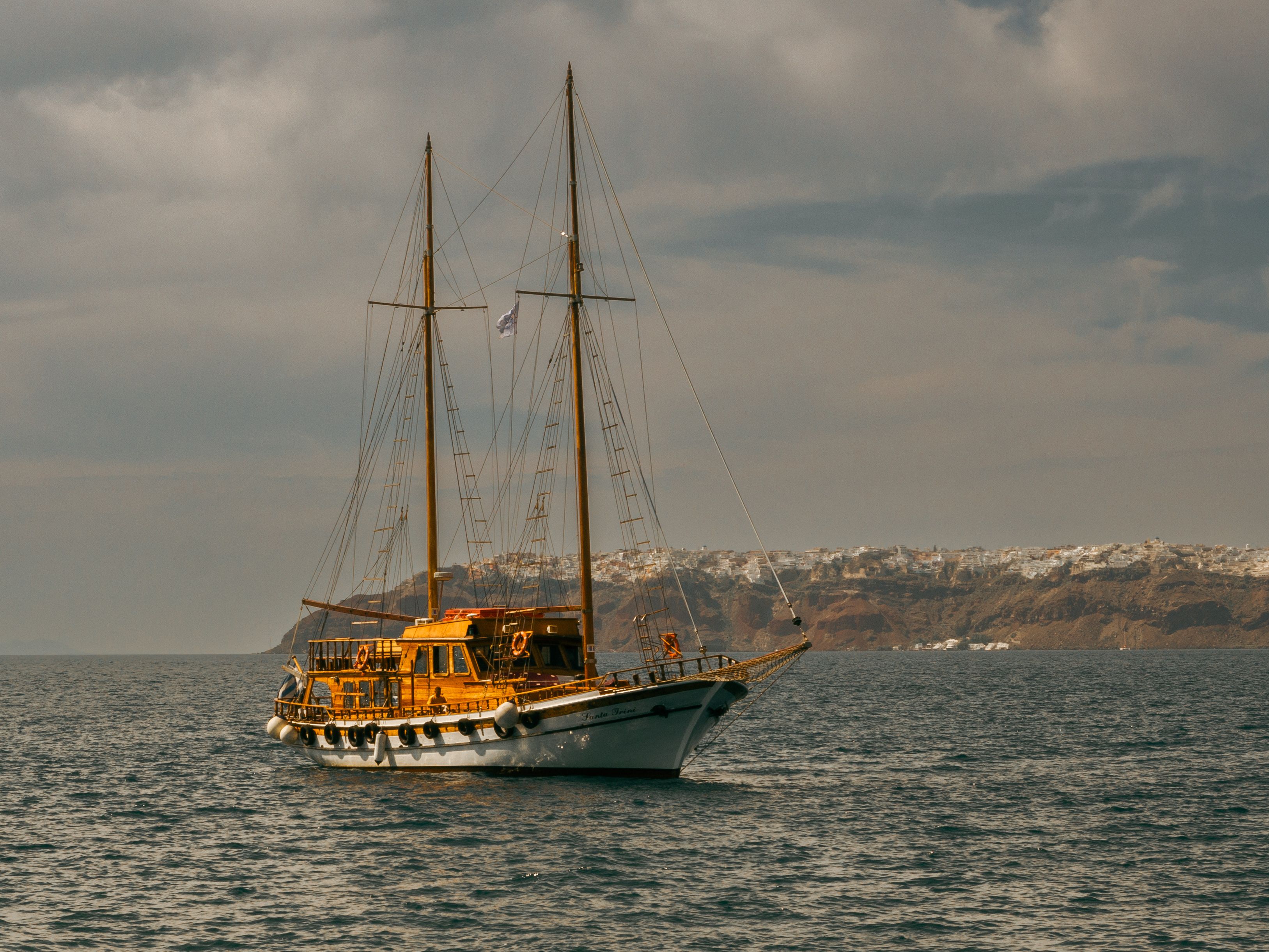 Unforgettable Corfu Private Yacht Cruise Review: Your Complete Guide to Greece's Most Stunning Coastline Review 2026 - A classic sailboat cruising on the open sea under cloudy skies, near a scenic coastline.